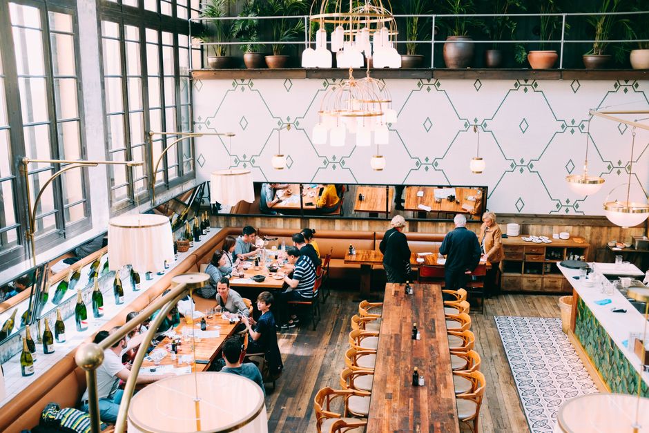 Spacious restaurant with stylish interior design, featuring wooden tables and a group of diners enjoying a meal.